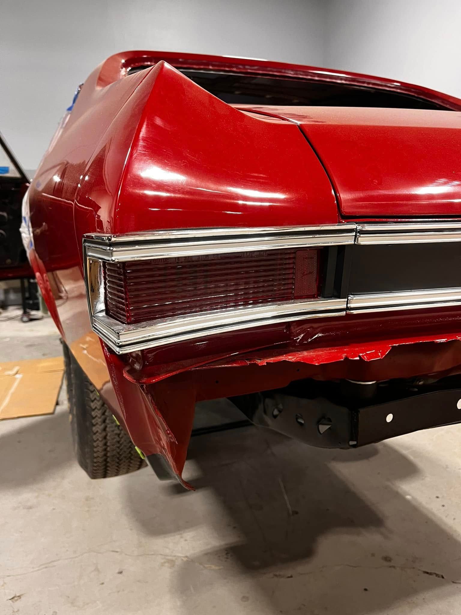 Red classic car rear with taillights and black bumper.