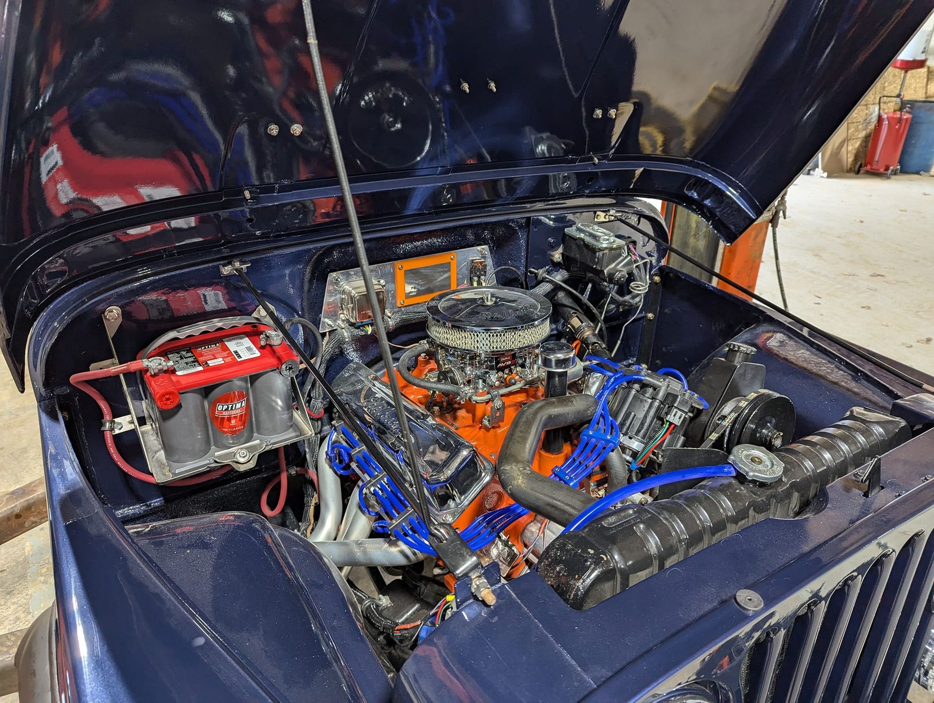 Blue Jeep engine bay with a large orange engine, opened hood.