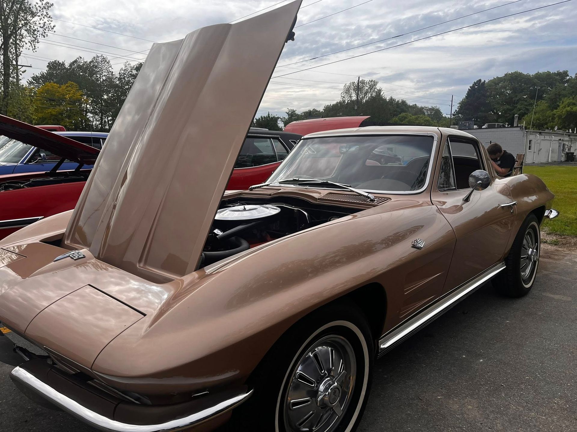 Classic tan Corvette with hood open, parked outdoors.