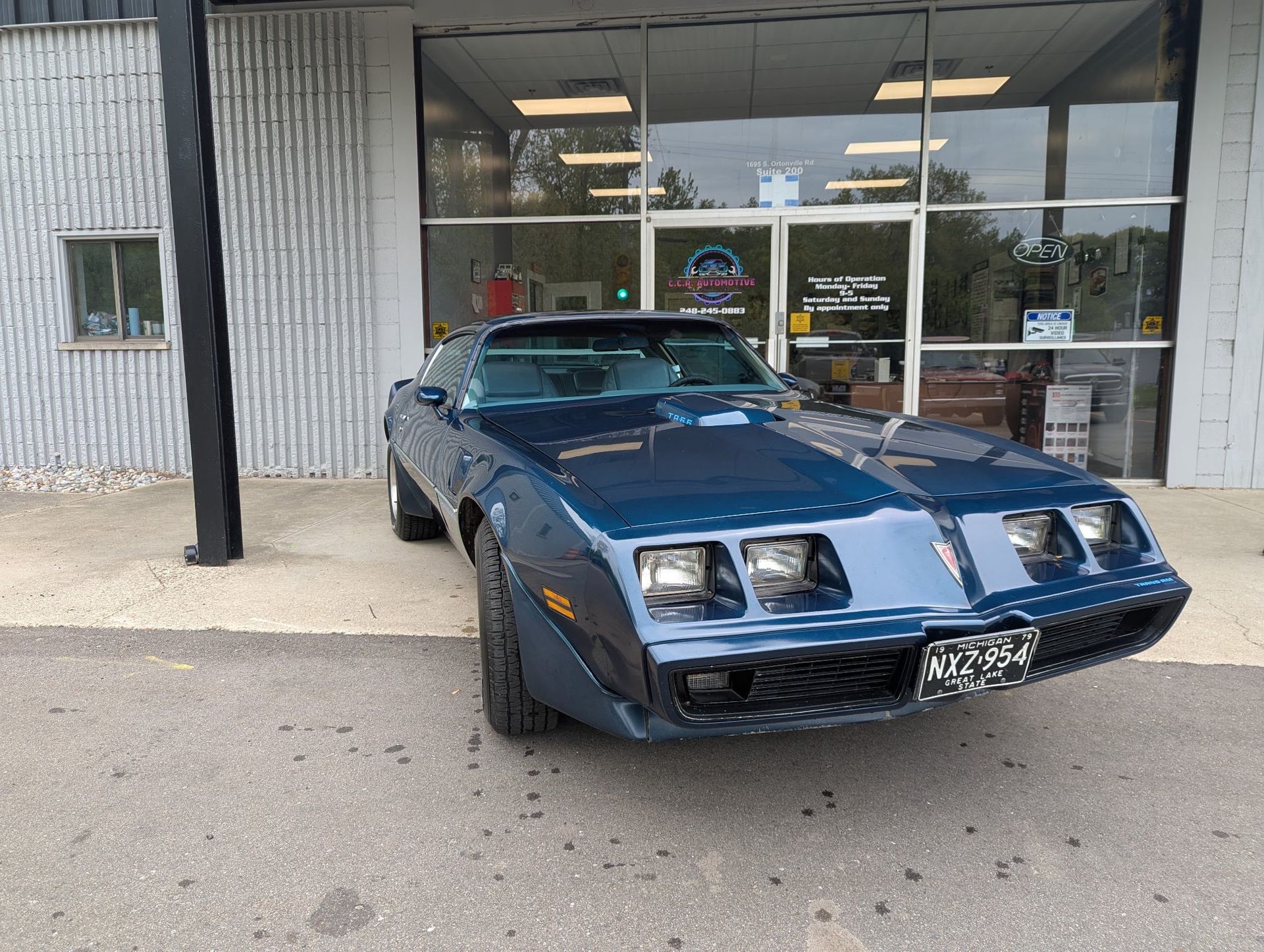 Dark blue Pontiac Firebird parked in front of a building.