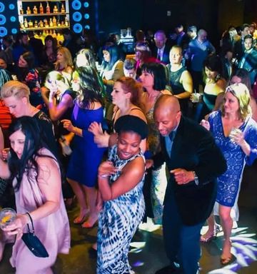People dancing in a nightclub with colorful lights. Men and women in formal attire enjoy themselves.