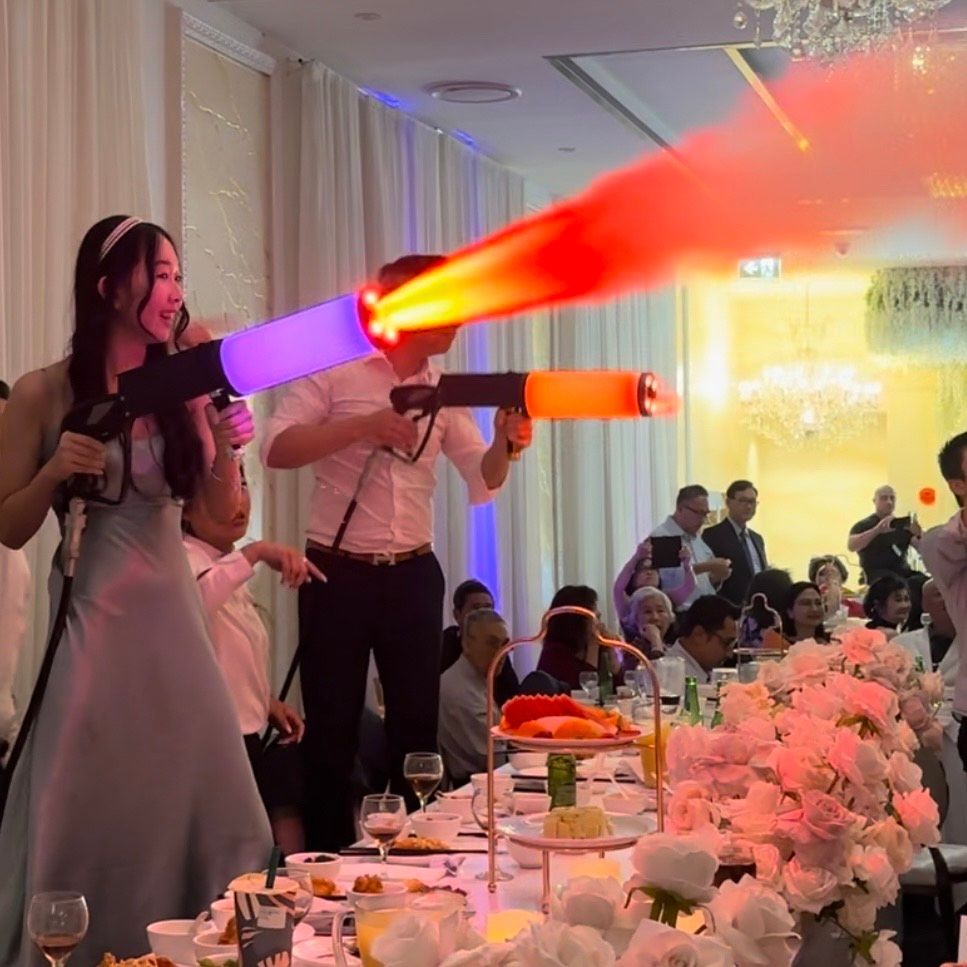 NEWLY WED COUPLE HOLDS CANON LIKE ITEMS SPEWING VIBRANT COLORS. 