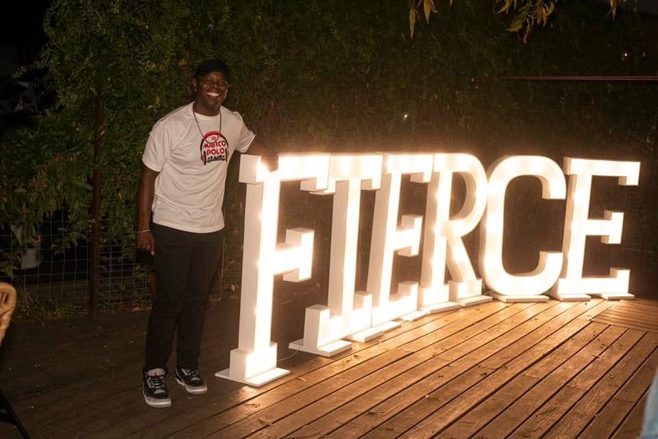 Man smiling next to a large, illuminated 