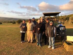 A group of people are posing for a picture in front of a golf cart.