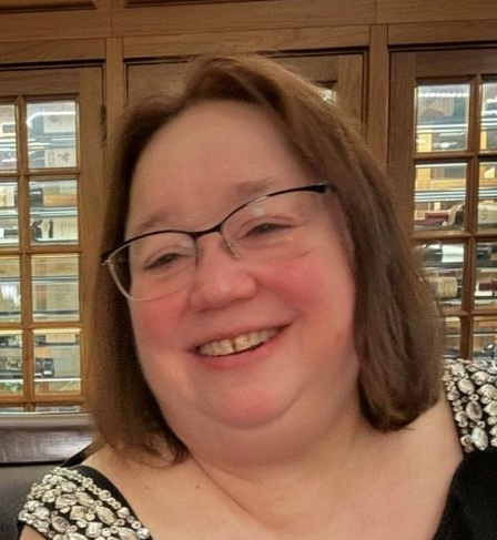 A close up of a woman wearing glasses and smiling.