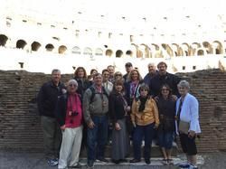 A group of people are posing for a picture in front of the colosseum.