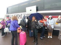 A group of people are standing in front of a bus with luggage.