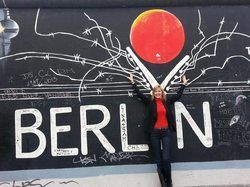 A woman is standing in front of a mural of berlin.