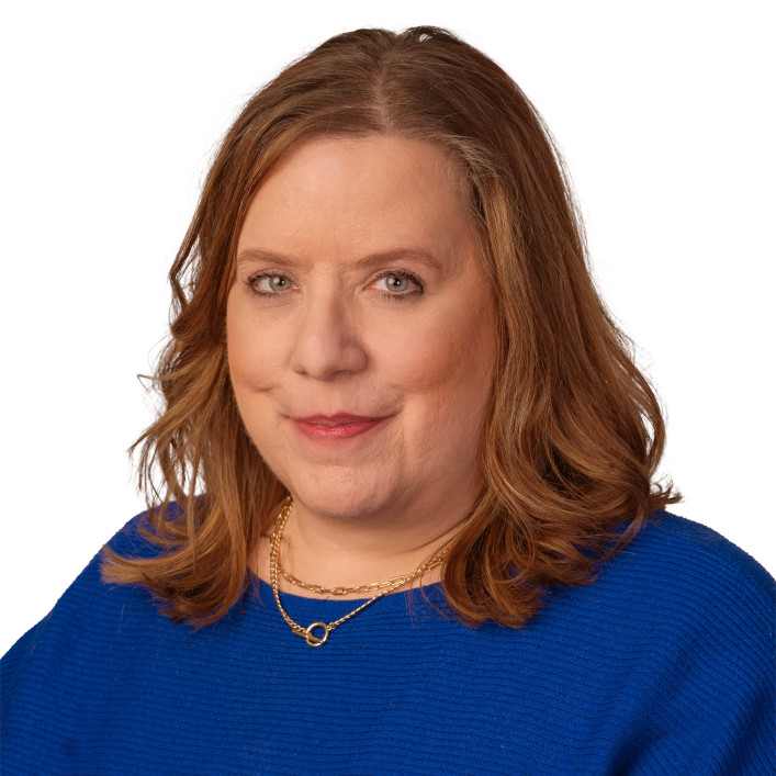 cheri headshot A woman is sitting in a chair and smiling for the camera.