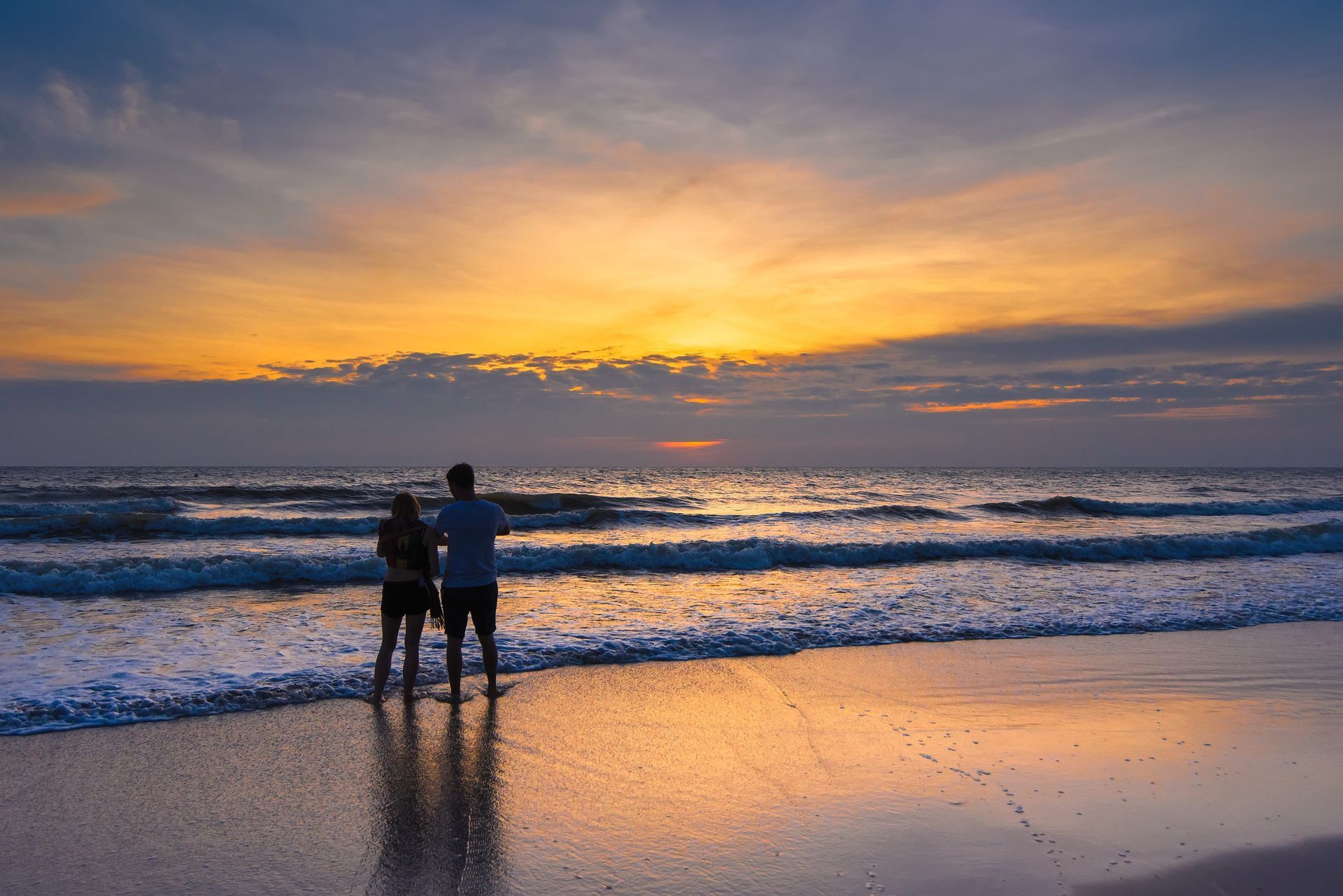 Couple watching the sunrise over the ocean during a milestone vacation