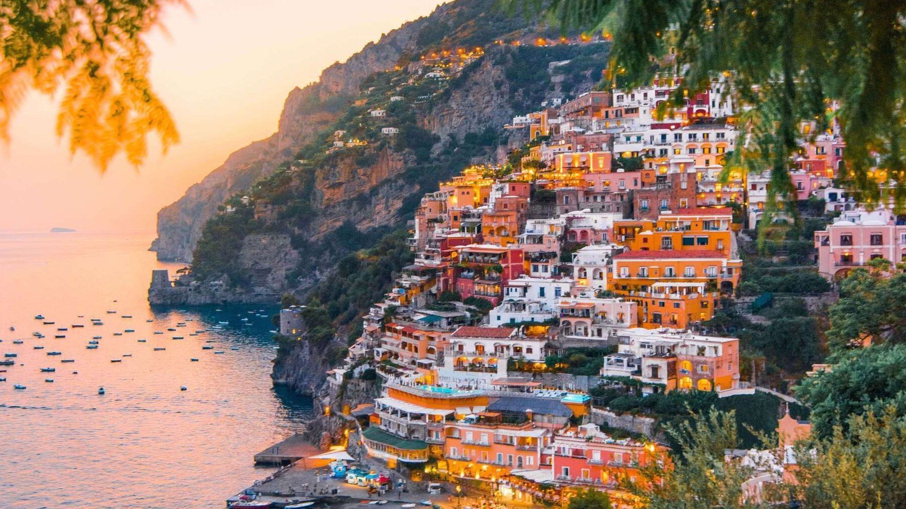 A small town on a cliff overlooking the ocean at sunset.