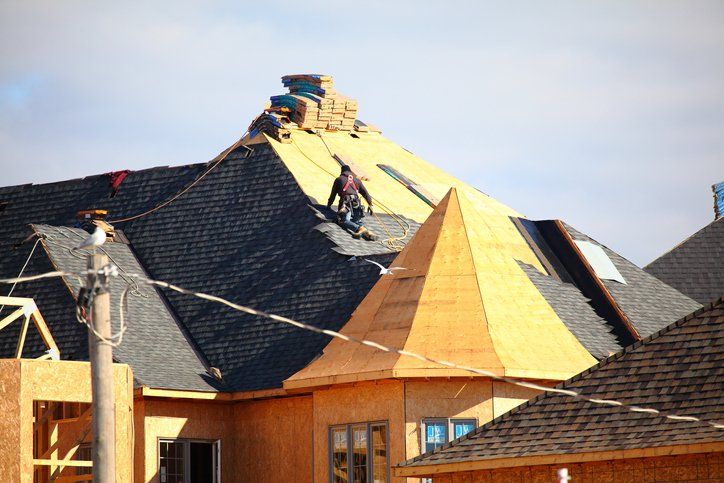 Roofer installing shingles on a new roof