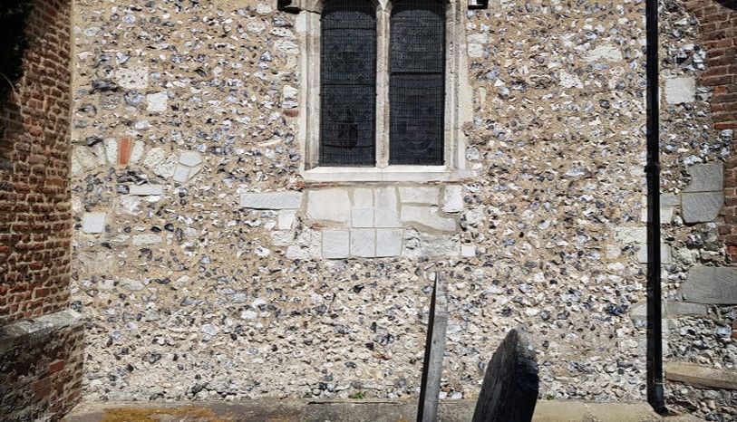 Stone church wall with window. Mixed flint and brick construction.