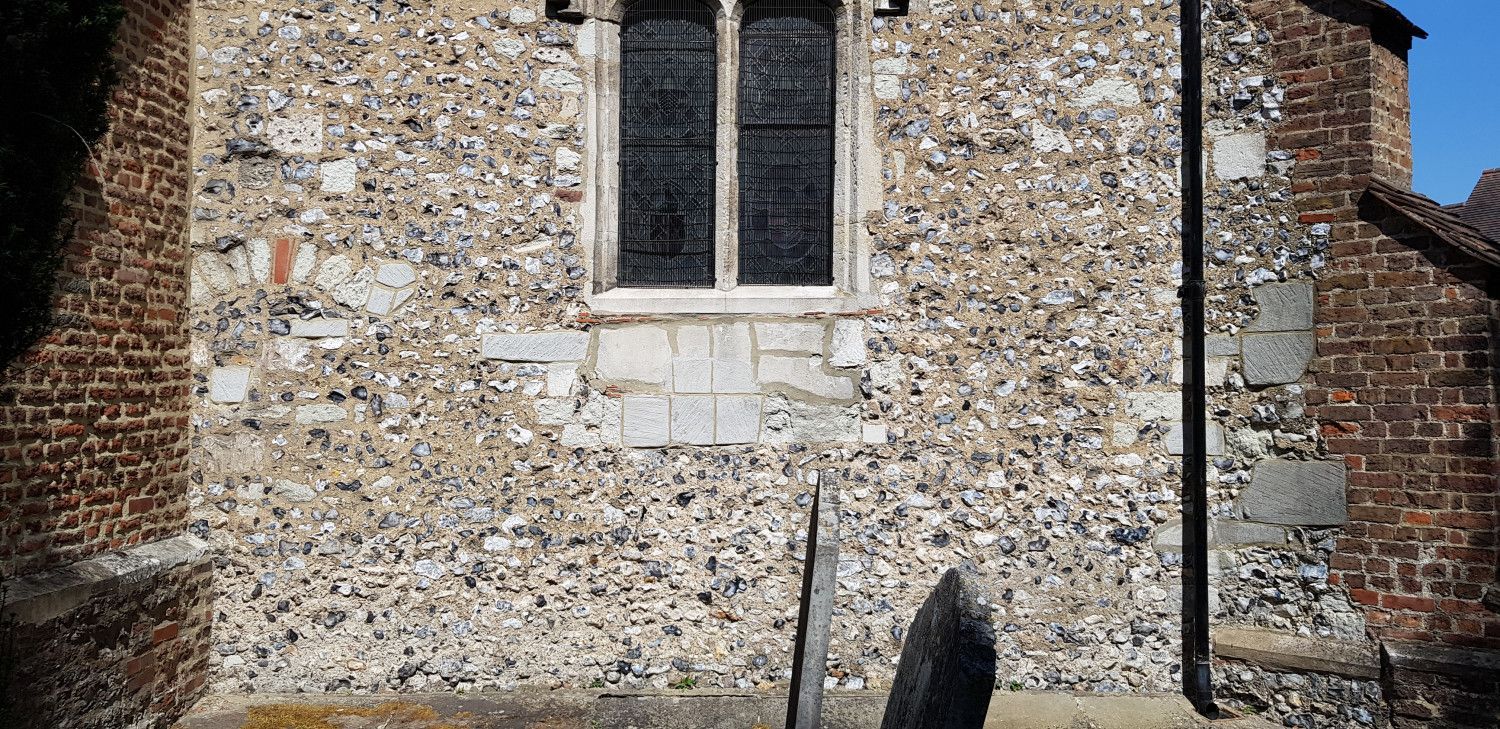 Stone church exterior with a window and brickwork details.