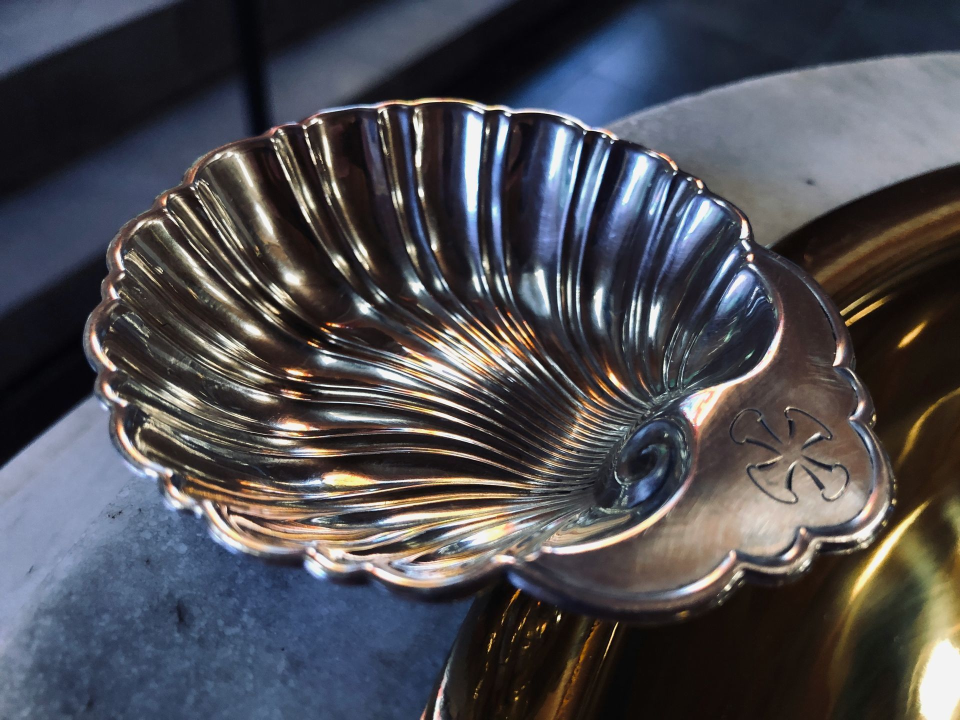 Silver seashell-shaped dish resting on a round, silver base. In a church setting.