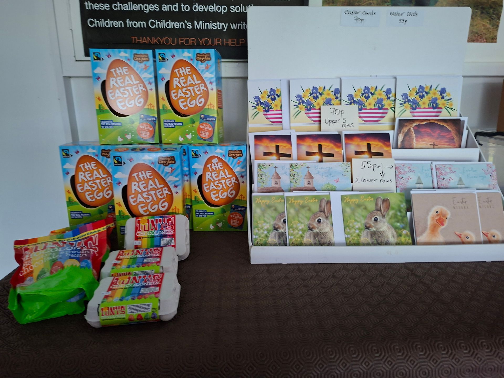 Easter-themed items for sale: chocolate eggs, cards with floral and bunny designs. Displayed on a table.