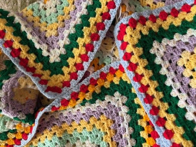 Crocheted granny square blanket, with colorful squares in green, red, yellow, and purple.