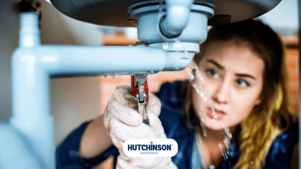 A woman is fixing a sink with a wrench.