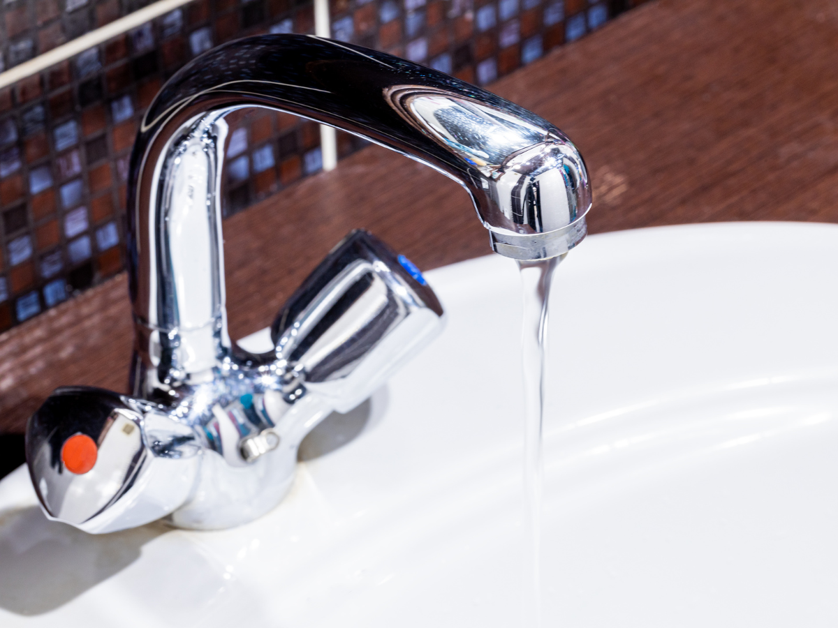 A close up of a bathroom sink with water running from the faucet.