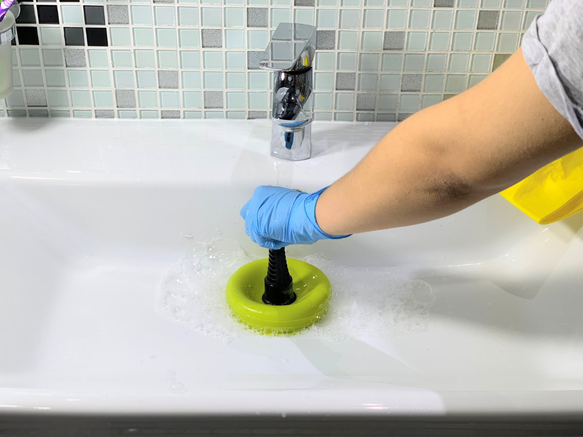A person is using a plunger to clean a bathroom sink. A person is using a plunger to clean a bathroom sink.