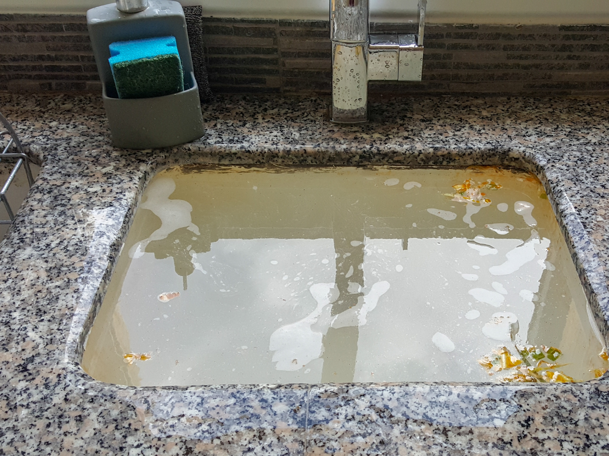 A kitchen sink with a sponge and soap dispenser on the counter.