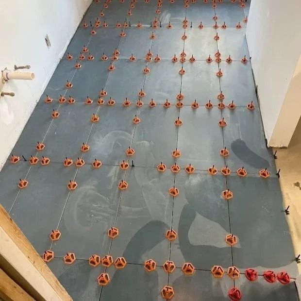Gray tiled floor with orange leveling clips set.