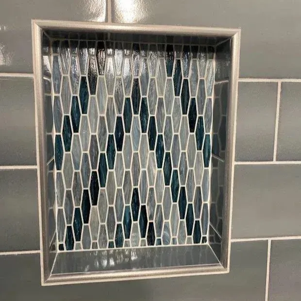 Person tiling a wall, using a level line. Vertical white tile, near a light switch and window.