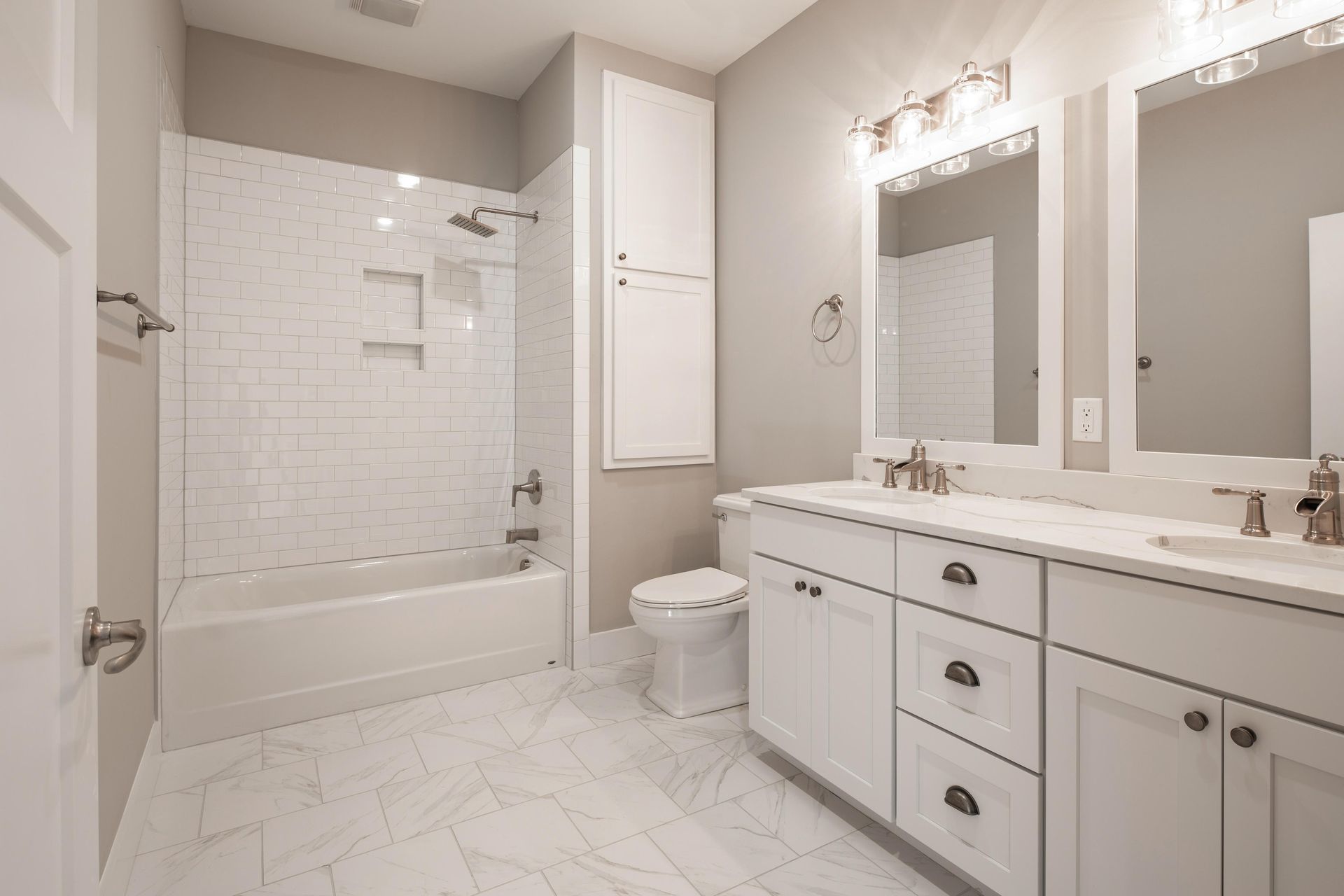 White bathroom with shower, vanity with two sinks, and toilet.