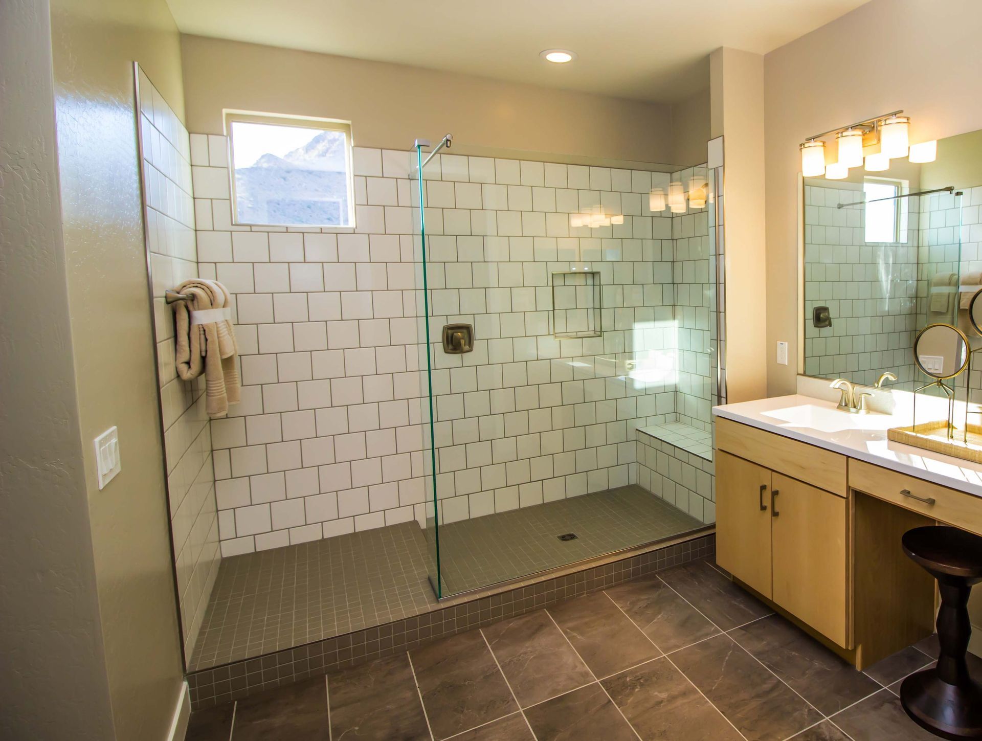Modern bathroom with a glass shower, vanity, and tan tile walls.