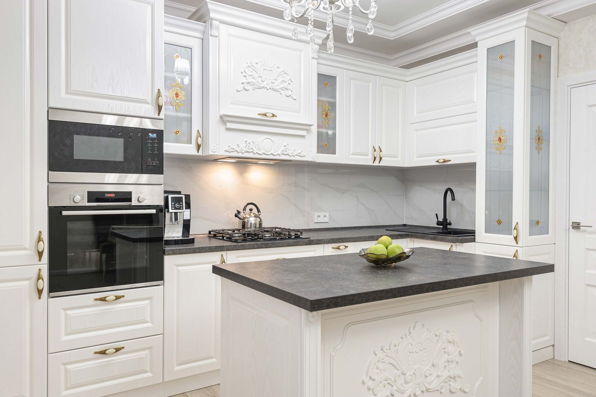 White kitchen with dark countertop island and appliances.