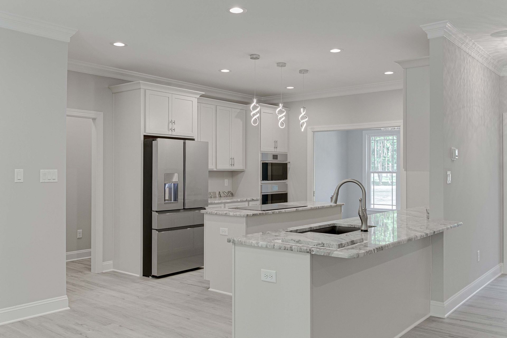 A modern kitchen with white cabinets, stainless steel appliances, and a granite countertop island.