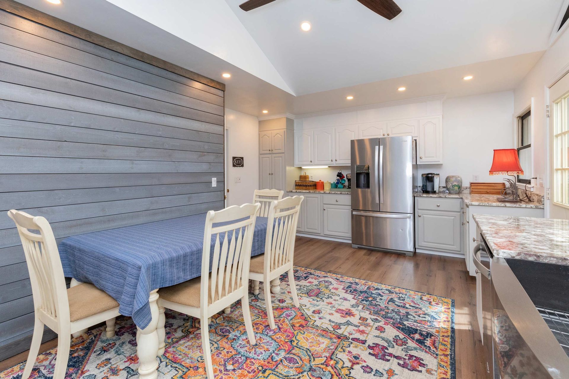 Dining room with a table, chairs, and kitchen with stainless steel appliances.
