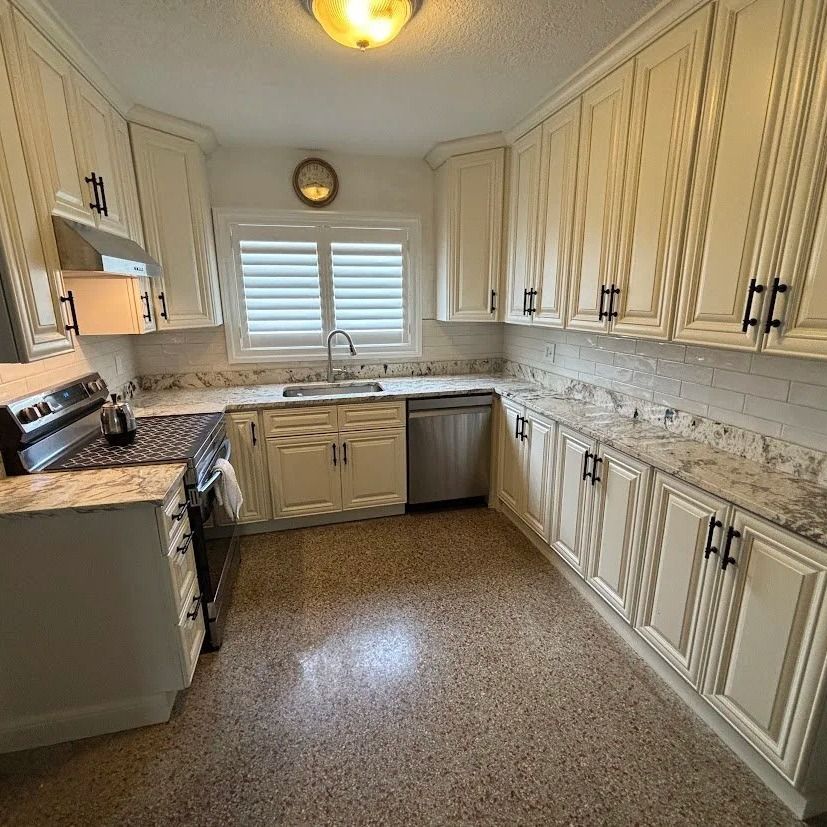 Cream-colored kitchen cabinets with black hardware, granite countertops, and stainless steel appliances.