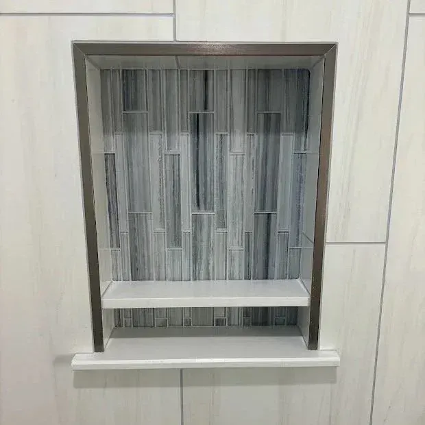 Person installing tiles in a room; tools on a table nearby.