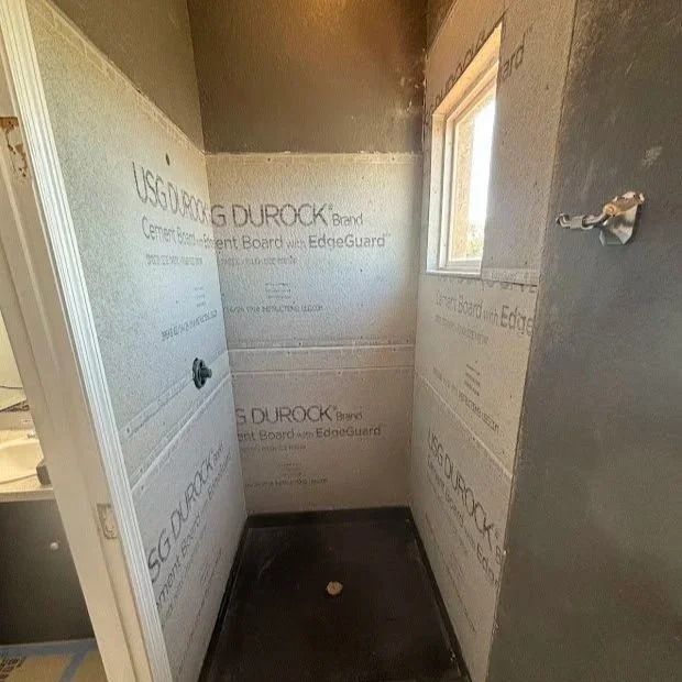 Shower stall with Durock cement board walls. Black shower pan, small window.