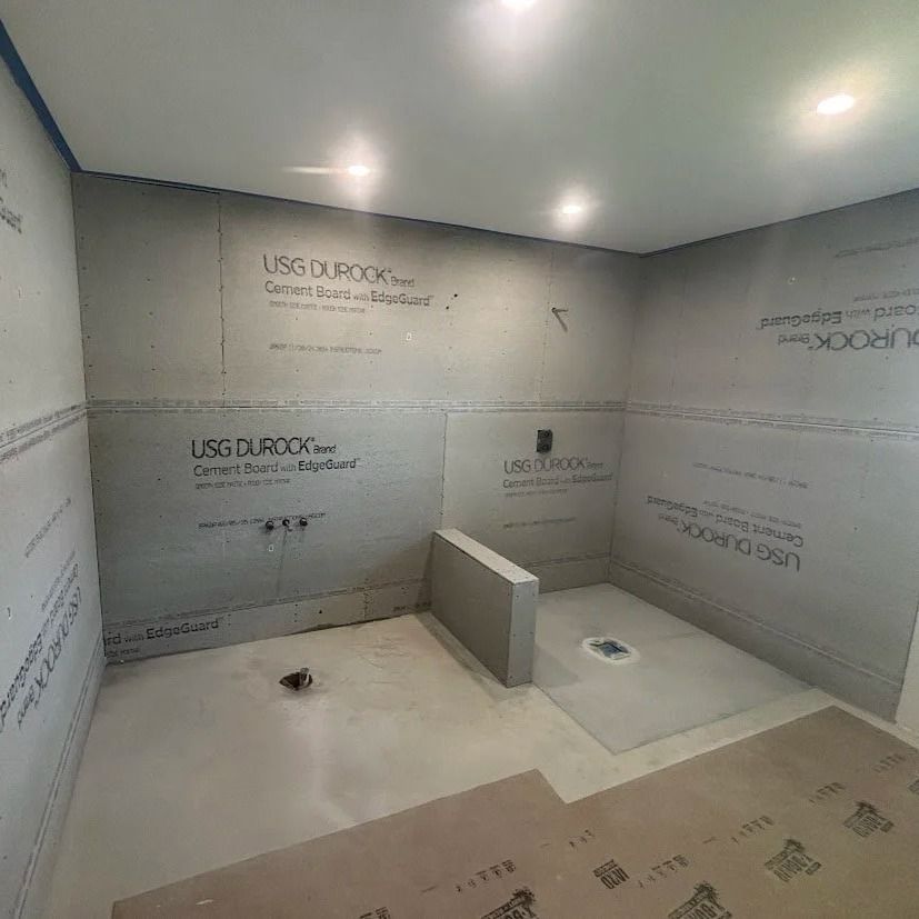 Bathroom under construction: walls and floor covered with gray cement board, shower base installed.