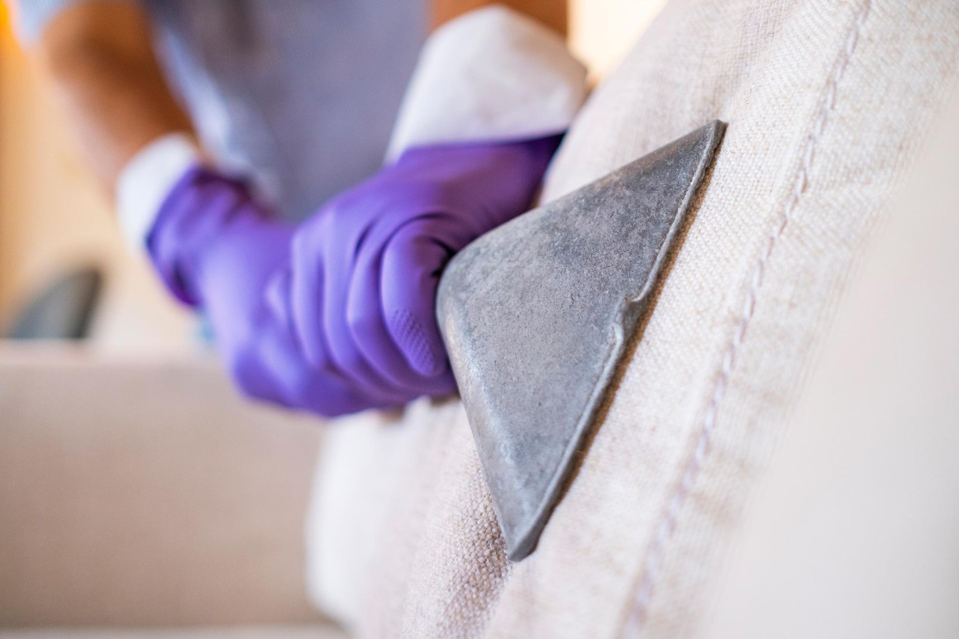 Hand With A Purple Protective Glove Cleans A Sofa's Upholstery With A Vacuum — Carson City, NV — Floor Masters