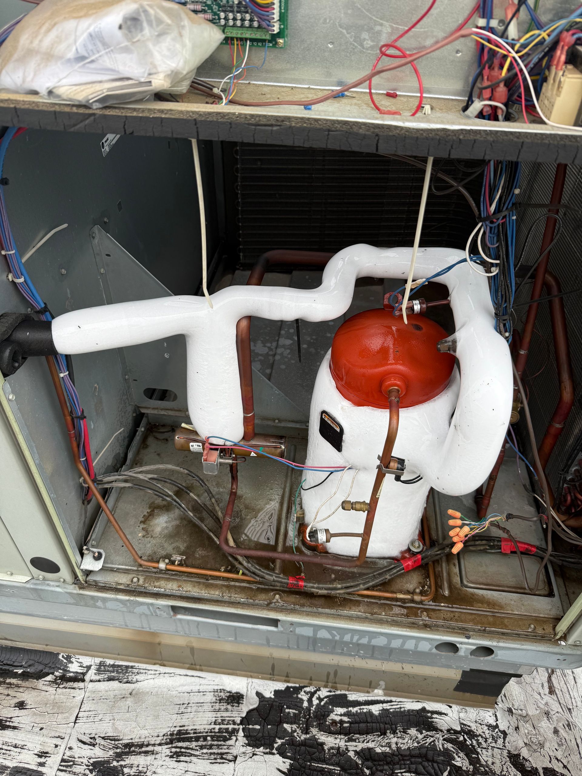 An air conditioning unit with frozen components, including the compressor and tubing. The unit is open.