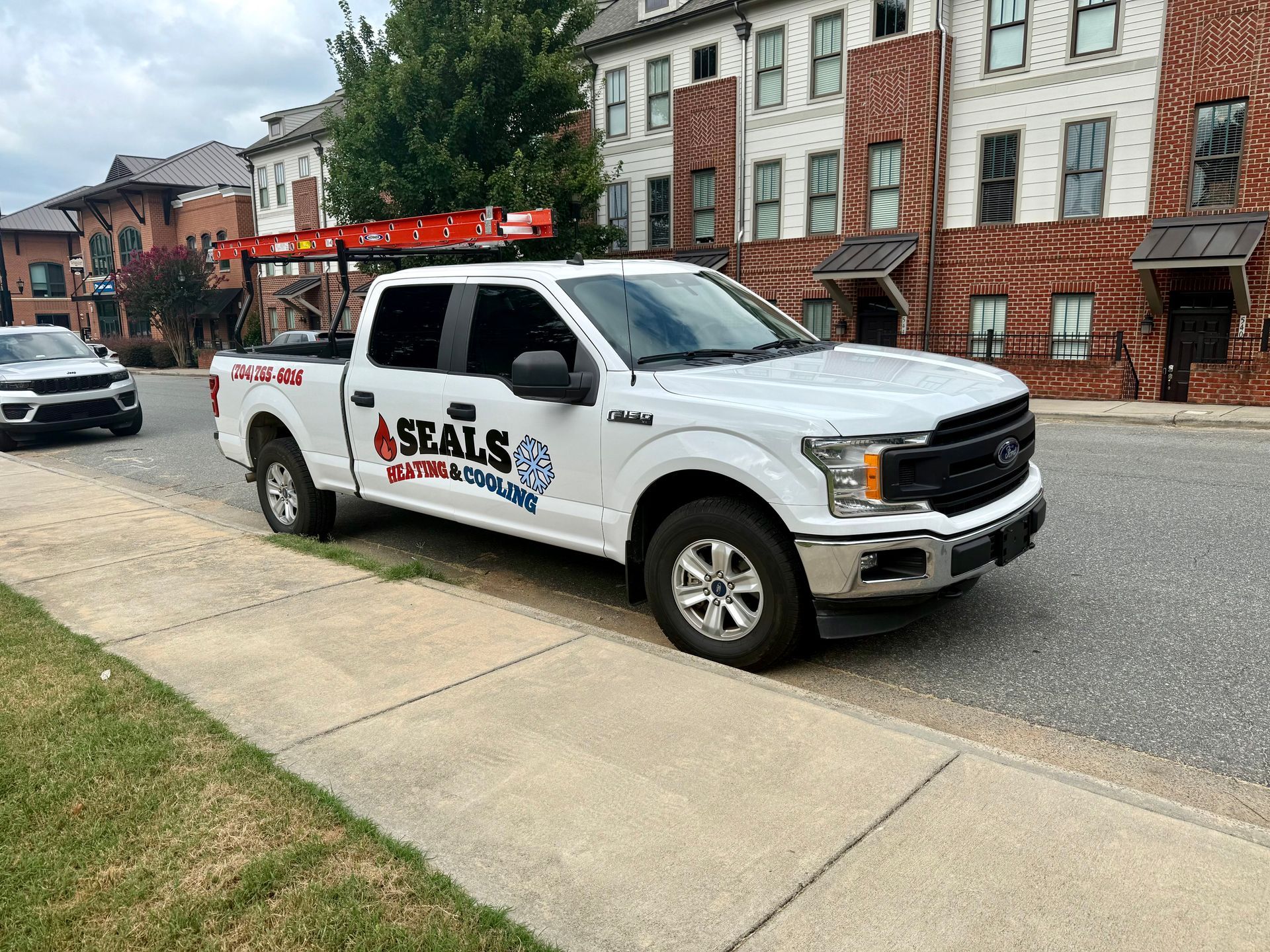 White Seals Electric truck parked on a street in front of brick buildings.