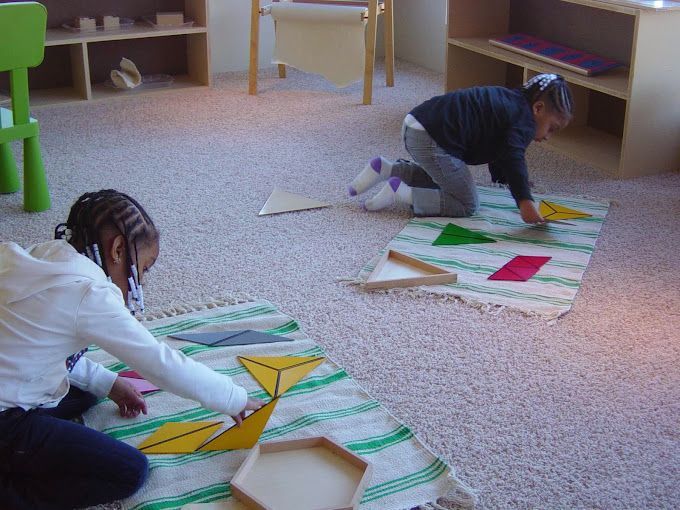 Two children are playing with geometric shapes on the floor