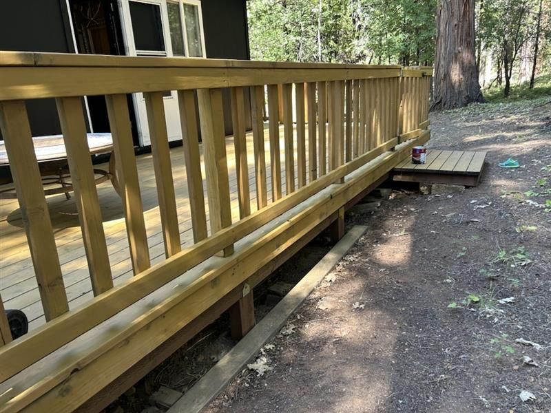 A person wearing white gloves and work clothes holds a metal trowel topped with a dollop of white drywall compound.