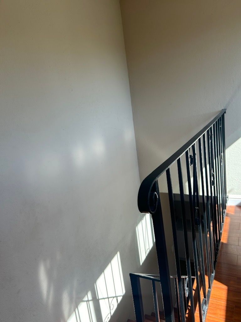 A small, jagged hole in a light-gray textured ceiling.
