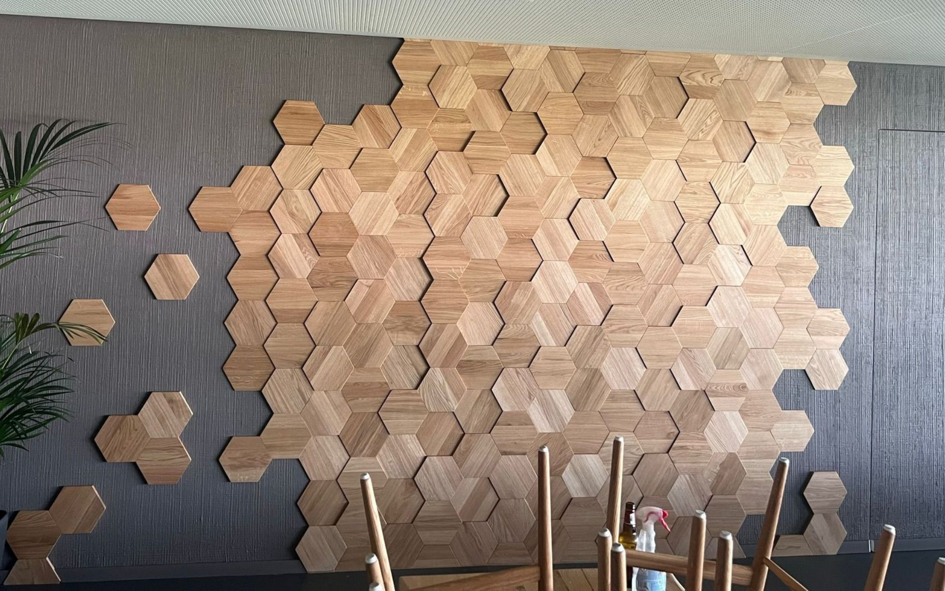 Un mur d'accent orné d'un motif géométrique d'hexagones en bois clair contrastant avec un mur gris foncé texturé.