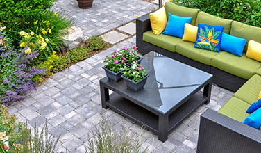 A patio with a couch and a coffee table with flowers on it.