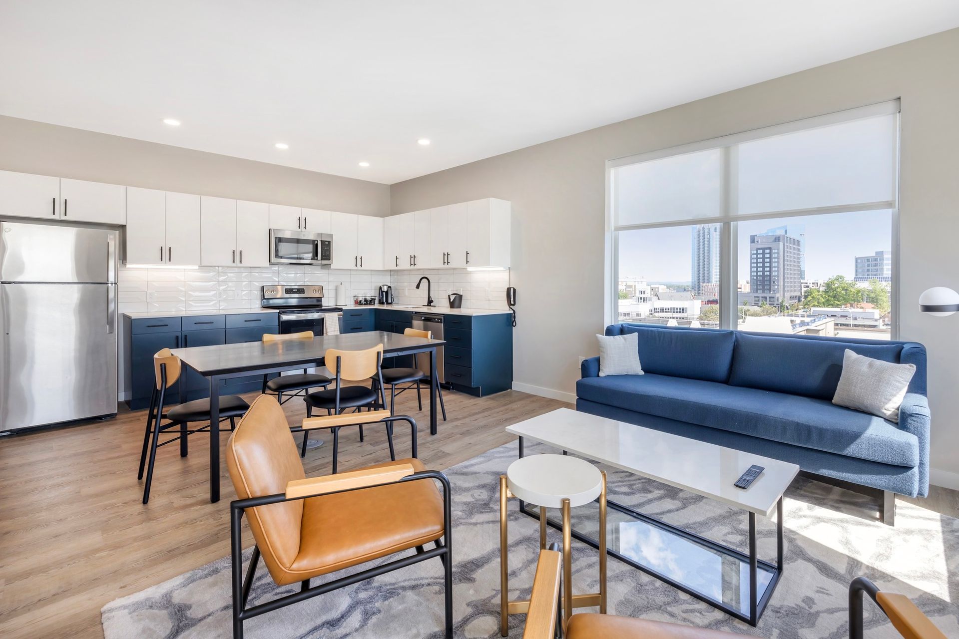 A living room with a couch , chairs , a table and a refrigerator.