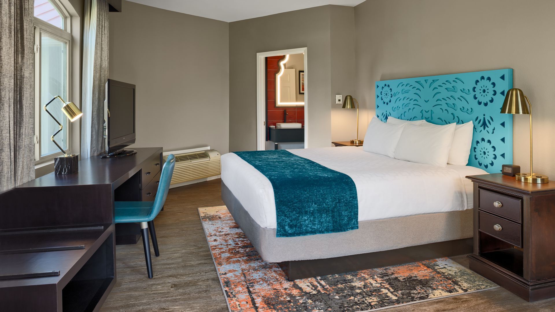 A hotel room with a king size bed , desk , nightstand and television.