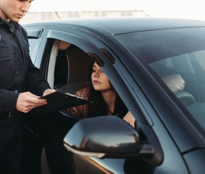 A Police Officer Is Talking To A Woman In A Car — Spencer Lawyers In Gosford, NSW