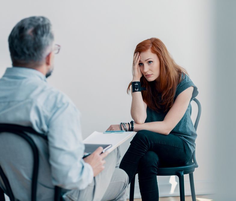 A Woman Is Sitting In A Chair Talking To A Man — Spencer Lawyers In Gosford, NSW