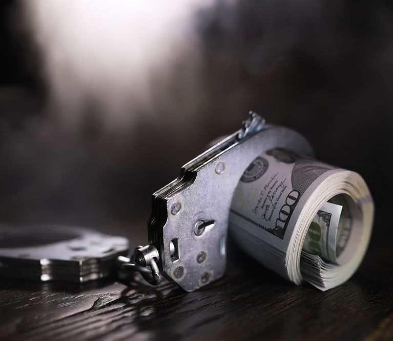 A Man In A Suit And Tie Is Wearing Handcuffs — Spencer Lawyers In Gosford, NSW