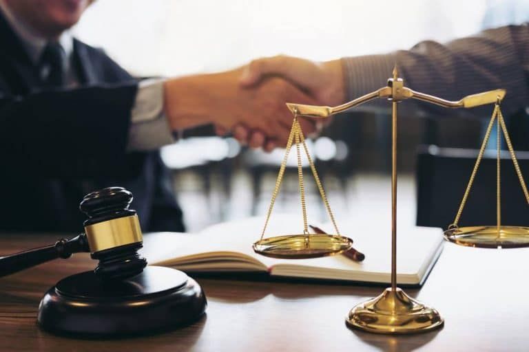 A Judge Shaking Hands With A Client In Front Of Scales Of Justice — Spencer Lawyers In Gosford, NSW